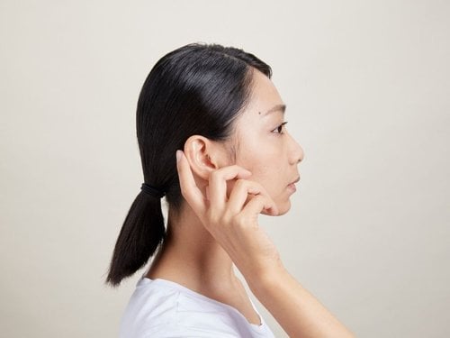 Photo of a woman changing the volume on her hearing aids